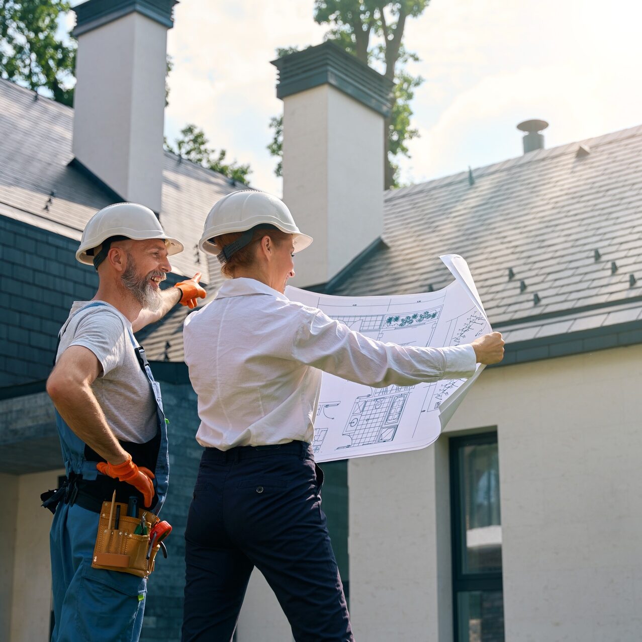 Builder and site supervisor using blueprints during building facade inspection